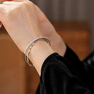 Close-up of double-layer silver bangle featuring pavé-set zircons and textured metal