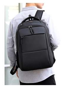 Uomo con grande zaino Oxford nero con design a scomparti multipli vicino a una finestra
