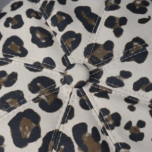 Detailed view of leopard print newsboy cap crown showing premium stitching and button