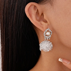 Close-up of sparkling rhinestone mesh earrings with white pearls on a model's ear