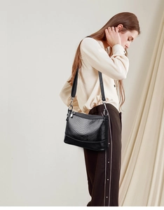 Detailed side view of black snakeskin texture handbag with adjustable silver metal strap