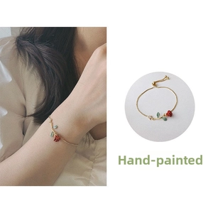 Detail of hand-painted red rose bracelet with gold chain and sparkling crystal accent