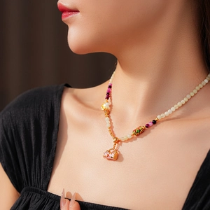 Detail of vintage enamel basket pendant necklace with pink beads on female model