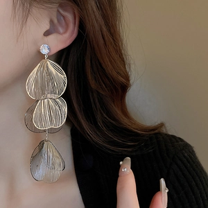 Close-up of champagne gold multi-layered leaf tassel earrings with sparkling rhinestone detail