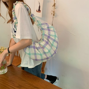 Detail of ruffled shoulder strap on purple and green plaid canvas crescent hobo bag