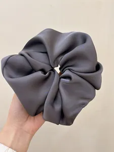 Detailed view of oversized dark grey satin scrunchie with a silk-like glossy finish