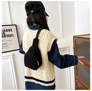 Detail of a black plush fleece mini crossbody chest bag with adjustable strap for kids