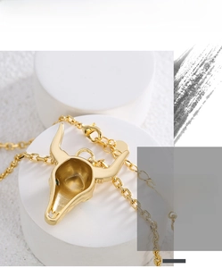 Detailed close-up of gold-plated bull skull pendant on a minimalist white pedestal