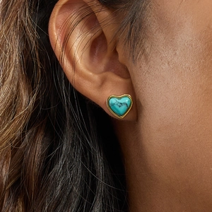 Élégantes boucles d'oreilles cœur en or avec turquoise portées par un mannequin