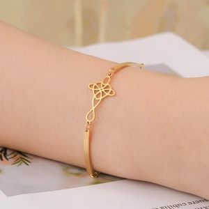 Elegant gold titanium steel cuff bracelet featuring a celtic knot charm on model wrist