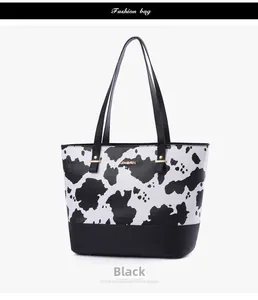 Detailed close-up of cow print tote bag with black leather base and gold JINGPIN metal plate