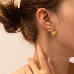 Detailed view of vintage gold fan earrings with zircon inlay on a model's ear