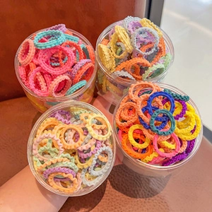 Detail of colorful wavy elastic hair ties stored in four transparent plastic canisters
