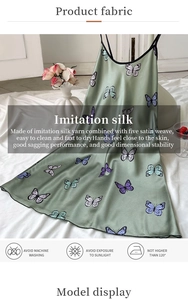Detail of green imitation silk slip dress with butterfly print and satin texture