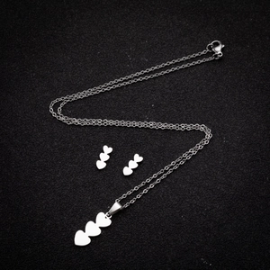 Elegant stainless steel heart necklace and earrings set on black background