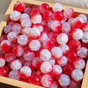 Macro detail of 10mm red and white gradient crackle glass beads in a wood tray