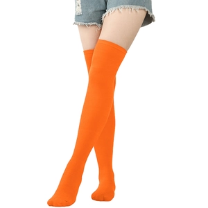Detail of bright orange over-the-knee knitted stockings with elastic fit and ribbed texture