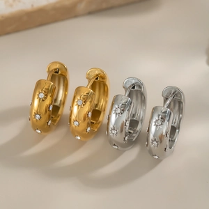 Detail view of 18K gold and silver C-shaped earrings with inlaid zircon star patterns