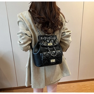 Detail of black quilted leather backpack with gold rotating locks and chain straps