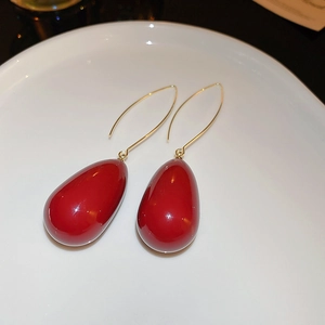 Détail de boucles d'oreilles perles rouges en forme de goutte et crochets dorés