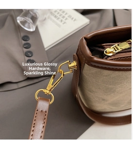 Detail of golden hardware and leather strap on beige canvas bucket bag