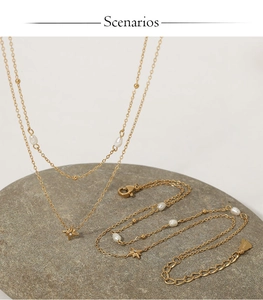 Detail of gold star pendant necklace and bracelet set with pearls on a grey stone