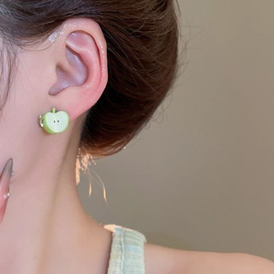 Close-up of a green apple slice stud earring worn on ear with enamel finish