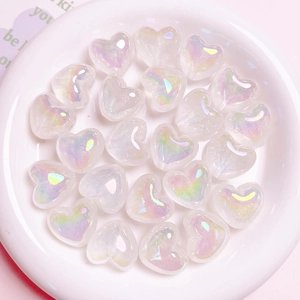 Macro shot of iridescent heart-shaped aurora beads in a white ceramic dish for DIY crafts