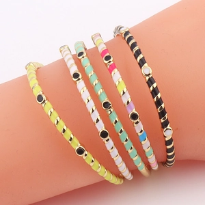Detail showing five colorful enamel stripe bracelets in yellow, white, green, and black