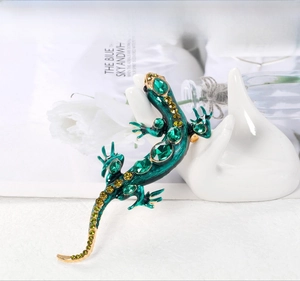 Détail d'une broche lézard en émail vert émeraude avec des pierres de cristal étincelantes
