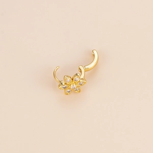 Boucle d'oreille fleur dorée avec pétales en zircon sur fond minimaliste et neutre