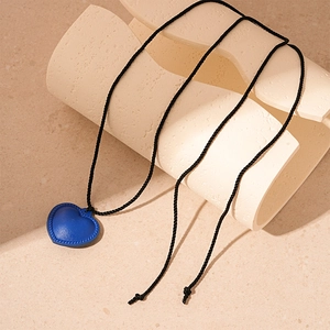 Detail of blue faux leather heart pendant on a black woven rope necklace for women