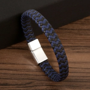 Braided leather couple bracelet with silver magnetic clasp on dark wood background