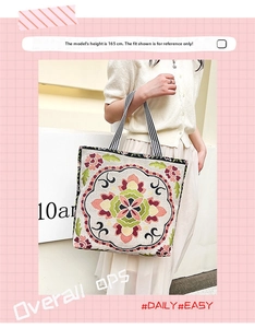 Detail of bohemian floral embroidery on a vintage canvas tote bag with striped straps
