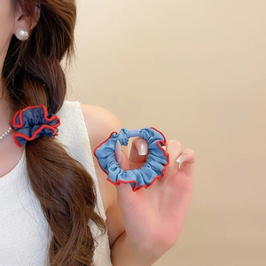 Detail showing blue denim scrunchie with red wavy trim on a braided hairstyle