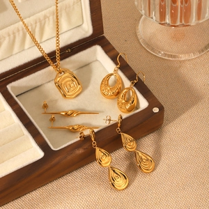 Close-up of gold-plated relief necklaces and textured earrings set in a wooden jewelry box