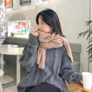 Winter cashmere-style scarf in camel paired with chunky grey knit sweater in a cafe