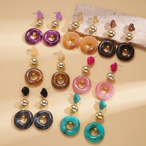 Flat lay of colorful acrylic resin geometric earrings with gold accents and stone decor