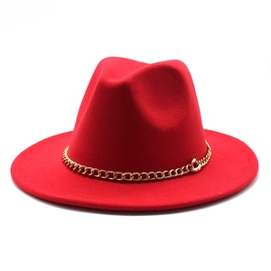 Detail view of red felt fedora hat featuring a stylish gold metal chain decoration