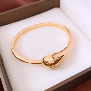 Detail of 18K gold plated teardrop bangle with hinge clasp in a luxury jewelry box