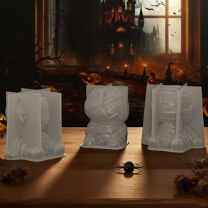 Three white silicone mummy molds for Halloween DIY candles and resin crafts on wooden surface