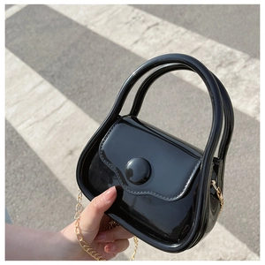 Detail showing the glossy black patent leather finish and gold chain strap of the mini bag