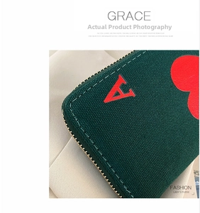 Detail of Ace of Hearts embroidery and gold zipper on dark green canvas wallet