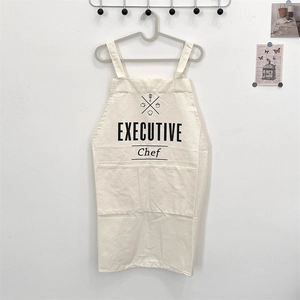 Detail of cream cotton linen apron featuring executive chef print and large pockets