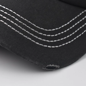 Detailed close-up of black cotton twill baseball cap brim with four-row white stitching