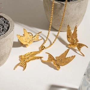 Golden swallow jewelry set with necklace earrings and ring on creative minimalist background