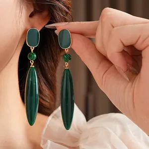 Vintage gold earrings with square malachite drop pendants on elegant model