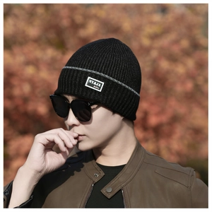Close-up of black ribbed knit beanie featuring NY&JA fashion label on a male model