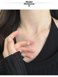 Close-up of s925 silver star necklace with pink zircon on model neck with black knitwear