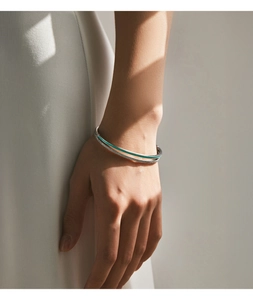 Macro shot of silver bangle featuring mint green enamel and pavé-set zircons on wrist